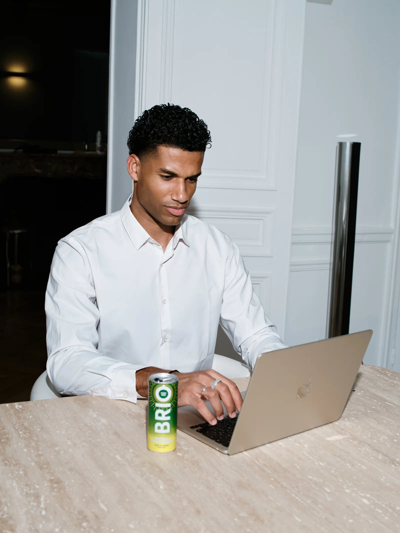 Un homme travaille sur son ordinateur, avec une canette BRIO sur la table